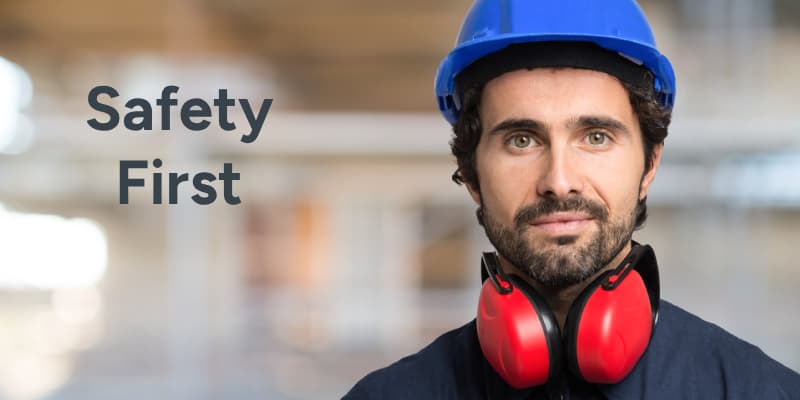 Man wearing blue hard hat and red ear defnders with safety first words displayed